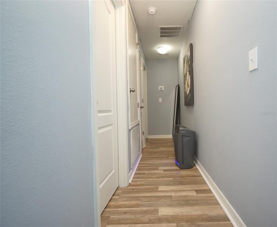 A hallway with light blue walls, wood-look flooring, and several white doors — 2709 LANTERN HILL AVENUE, BRANDON, FL