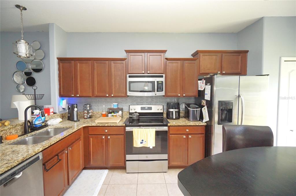 A kitchen features wood cabinets, granite countertops, stainless steel appliances, and a tile backsplash — 2709 LANTERN HILL AVENUE, BRANDON, FL
