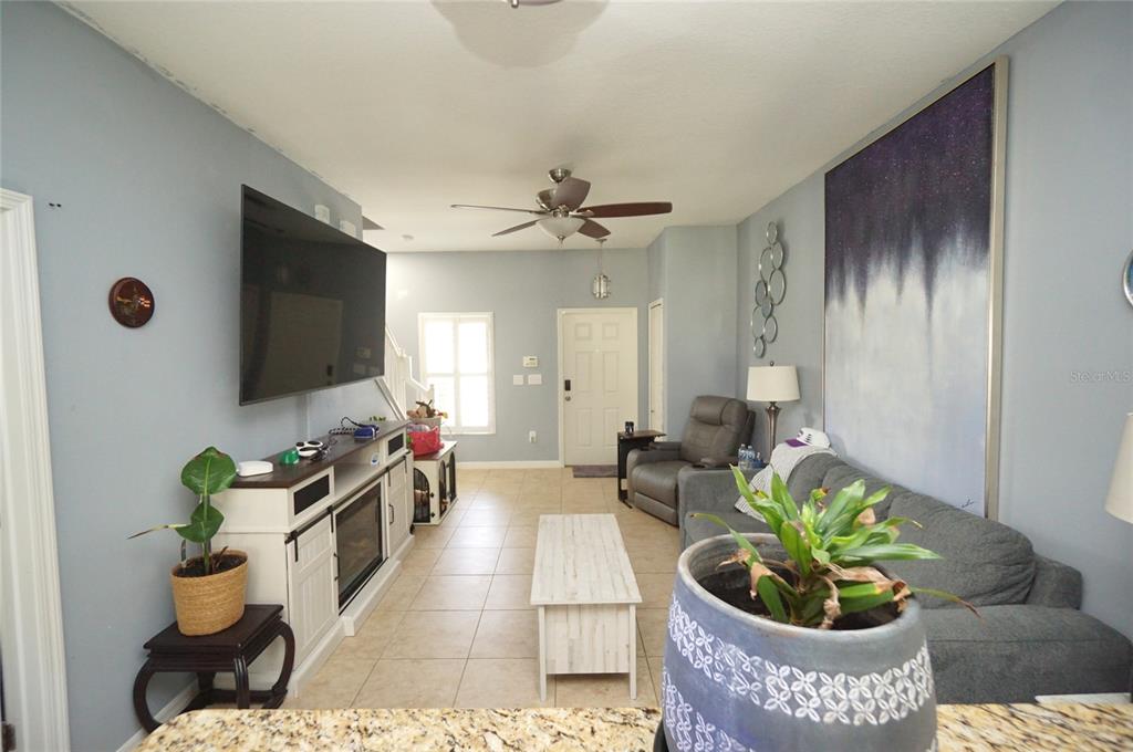 A living room features a gray sofa, a television mounted above a fireplace console, and tile flooring — 2709 LANTERN HILL AVENUE, BRANDON, FL