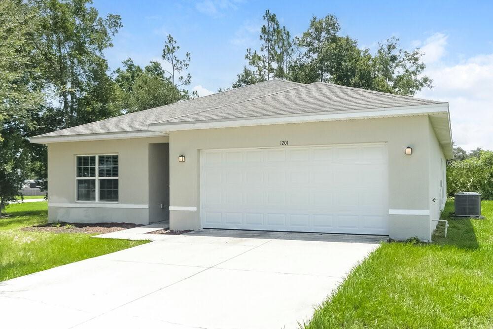 A single-story house with a beige stucco exterior, a two-car garage, and a concrete driveway — 1201 CROYDON CIRCLE, KISSIMMEE, FL