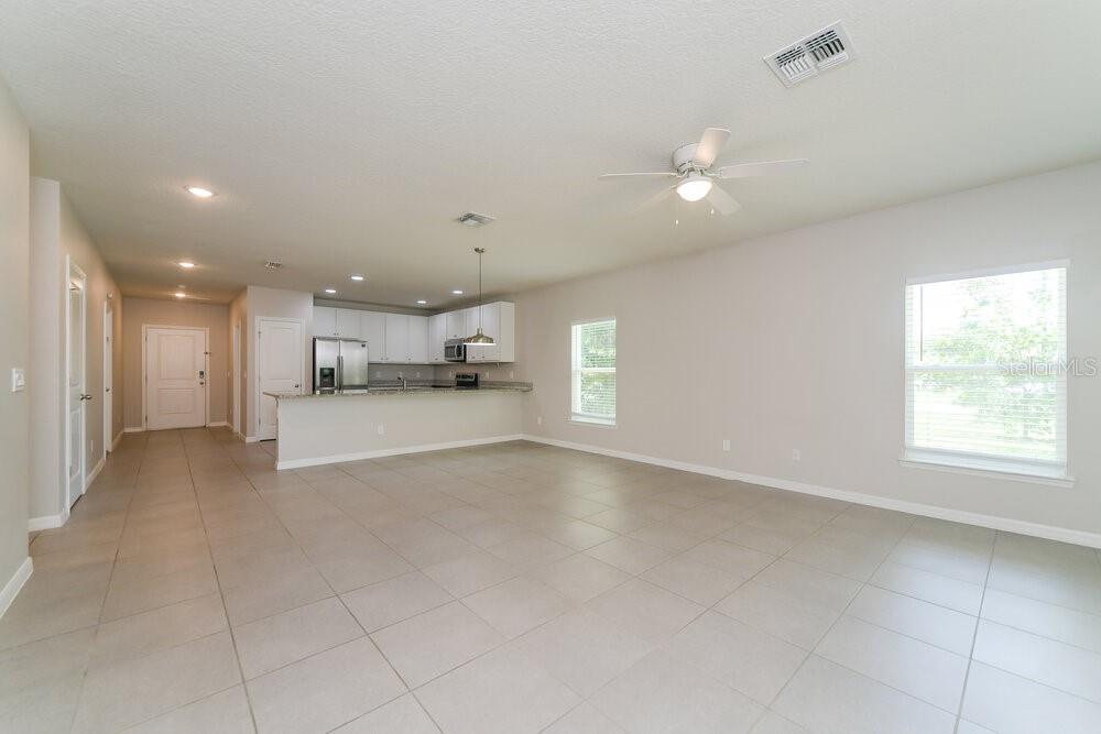 An open-concept kitchen and living area with tile flooring, white cabinets, and a ceiling fan — 1201 CROYDON CIRCLE, KISSIMMEE, FL