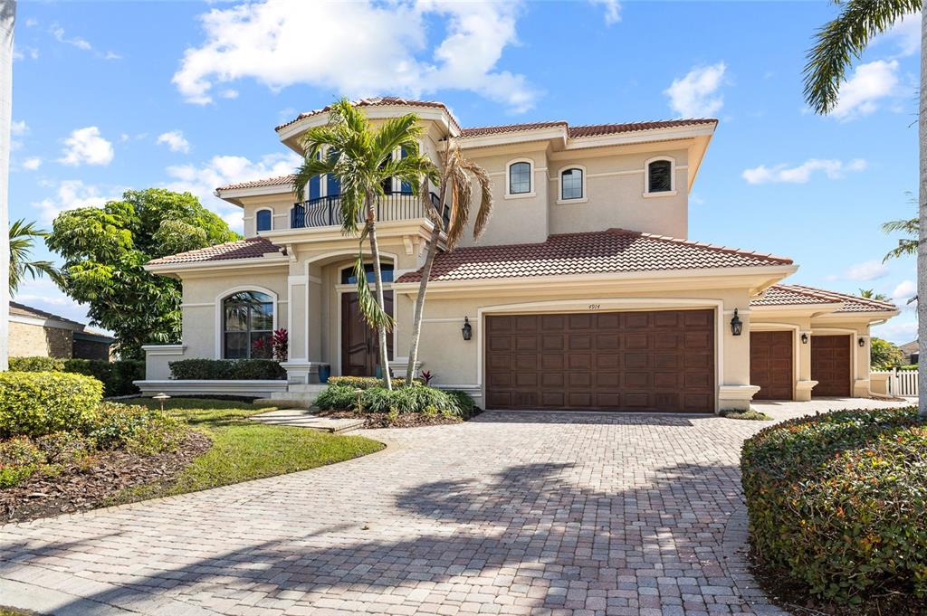 A two-story waterfront house with a red tile roof sits beside a canal with boats — 4914 59TH AVENUE S, ST PETERSBURG, FL