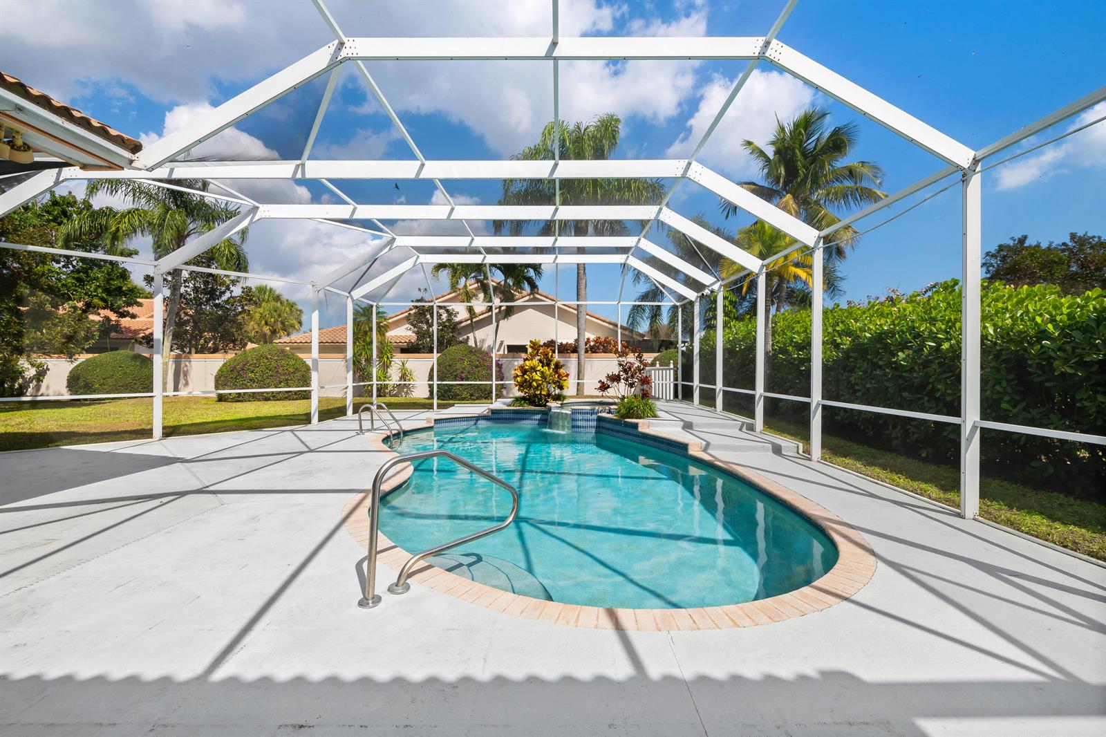 A screened-in swimming pool with a waterfall feature sits on a concrete patio — 2730 Tecumseh Drive, West Palm Beach FL 33409, WEST PALM BEACH, FL
