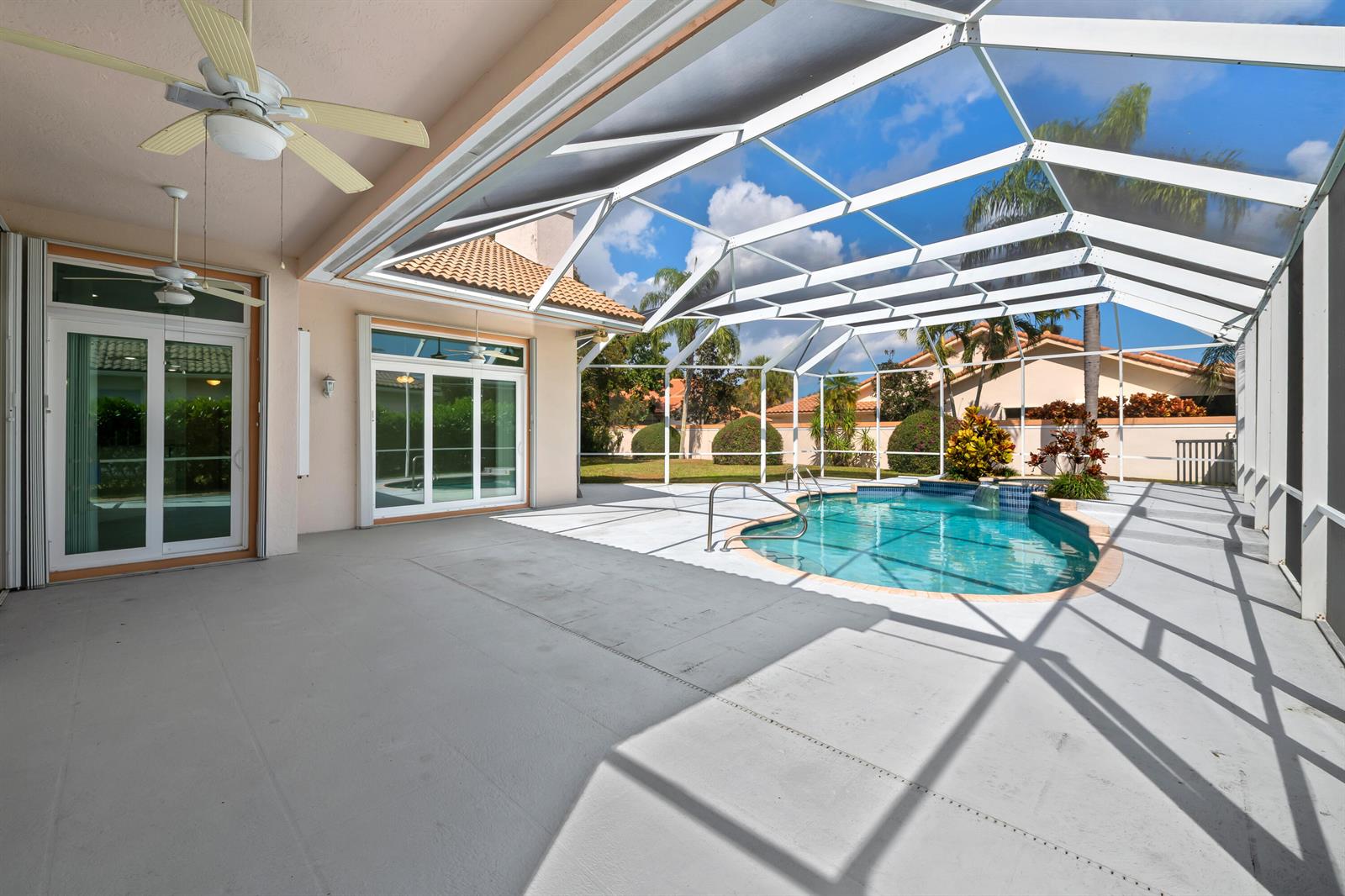 A covered patio features a swimming pool enclosed by a screen cage and ceiling fans — 2730 Tecumseh Drive, West Palm Beach FL 33409, WEST PALM BEACH, FL