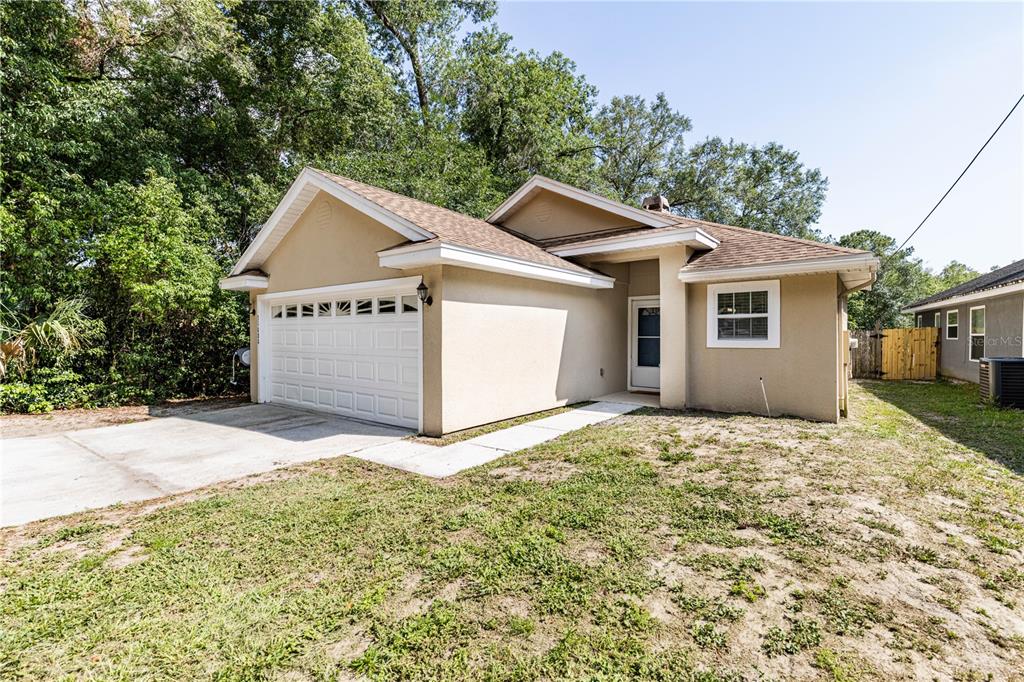 A tan, single-story house with a white garage door and a concrete walkway — 31080 LOCHMORE CIRCLE, SORRENTO, FL