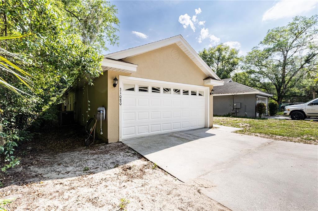 A beige detached garage with a white sectional door sits on a concrete driveway — 31080 LOCHMORE CIRCLE, SORRENTO, FL