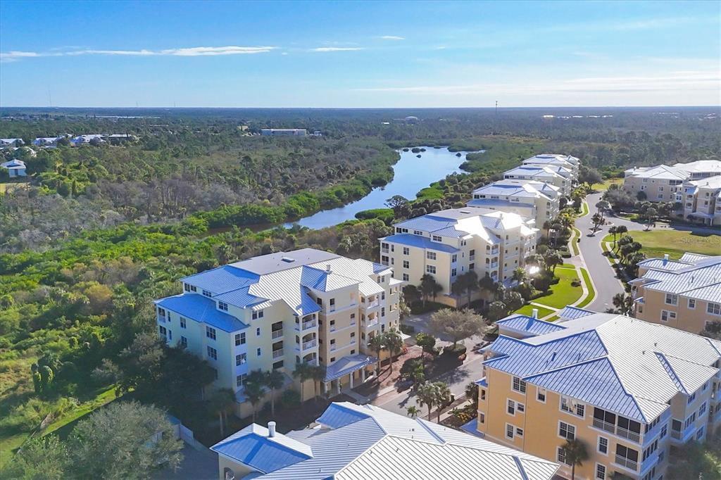 An aerial view shows several multi-story apartment buildings situated near a winding river and trees — 8541 AMBERJACK CIRCLE UNIT 203, ENGLEWOOD, FL