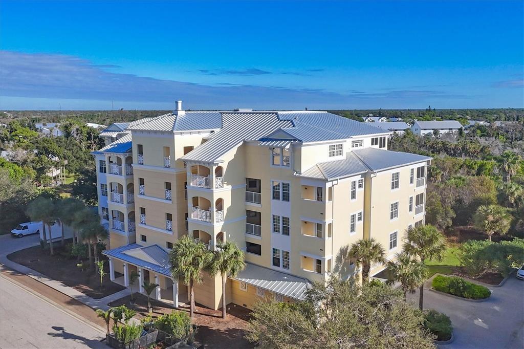 An aerial view of a multi-story yellow apartment building with a metal roof and balconies — 8541 AMBERJACK CIRCLE UNIT 203, ENGLEWOOD, FL