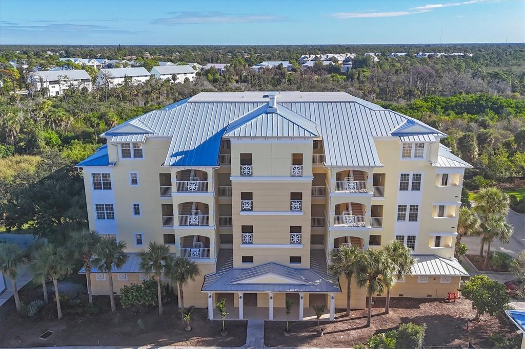 An aerial view of a multi-story yellow apartment building with a metal roof — 8541 AMBERJACK CIRCLE UNIT 203, ENGLEWOOD, FL
