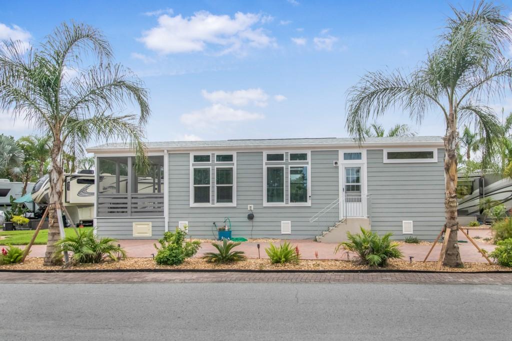 A light gray manufactured home features a screened porch, two palm trees, and a patio — 6820 AMANDA VISTA CIRCLE, LAND O LAKES, FL