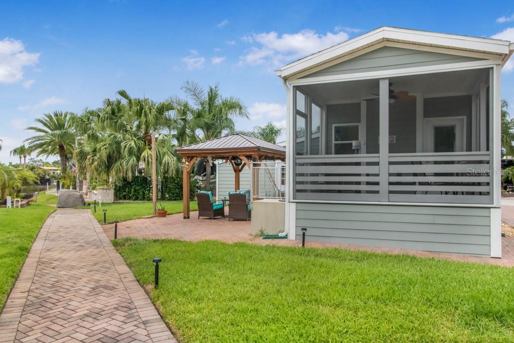 A paved walkway leads to a screened-in porch and a gazebo on a grassy lawn — 6820 AMANDA VISTA CIRCLE, LAND O LAKES, FL