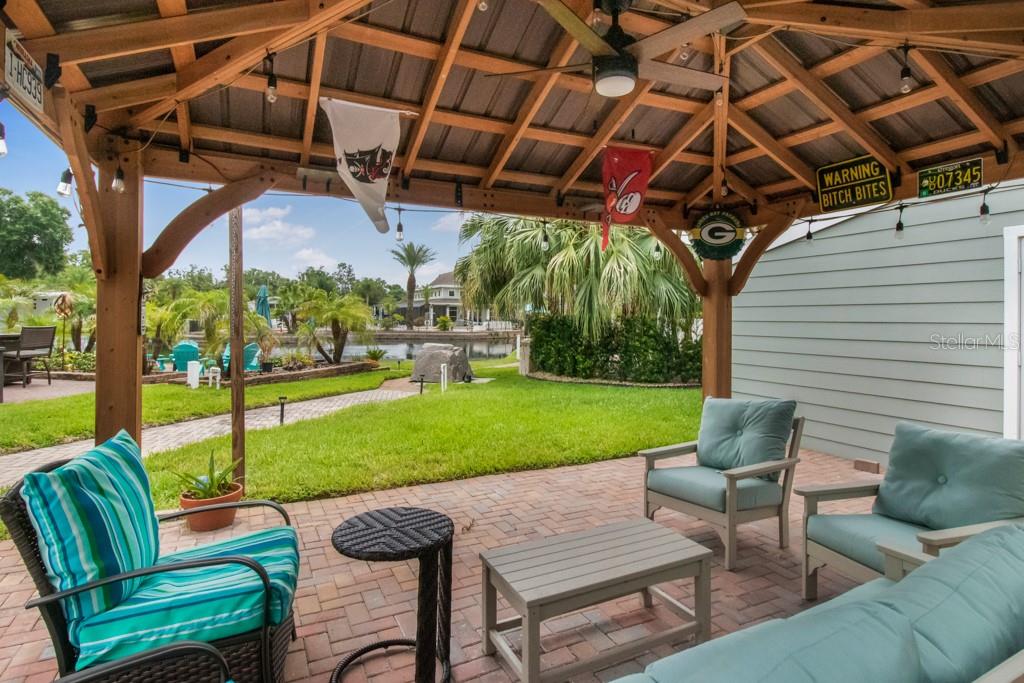 A covered brick patio features outdoor seating, a ceiling fan, and views of a grassy lawn — 6820 AMANDA VISTA CIRCLE, LAND O LAKES, FL