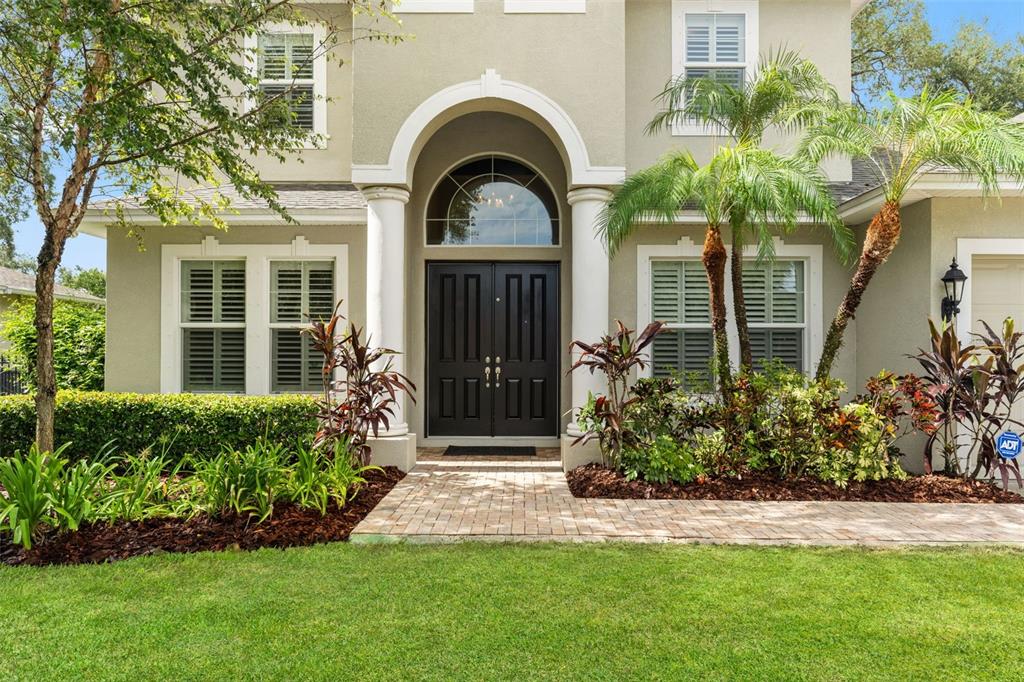 The exterior of a two-story house features a brick walkway leading to a black double door — 2112 CARROLL LANDING DRIVE, TAMPA, FL