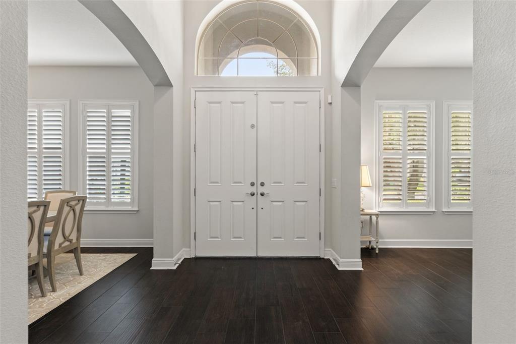 A bright entryway features dark hardwood floors, white double doors, and arched windows — 2112 CARROLL LANDING DRIVE, TAMPA, FL