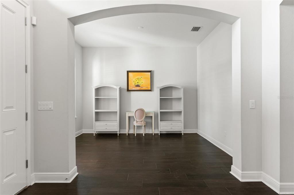 A room with dark wood floors, two white bookshelves, a desk, and a chair — 2112 CARROLL LANDING DRIVE, TAMPA, FL