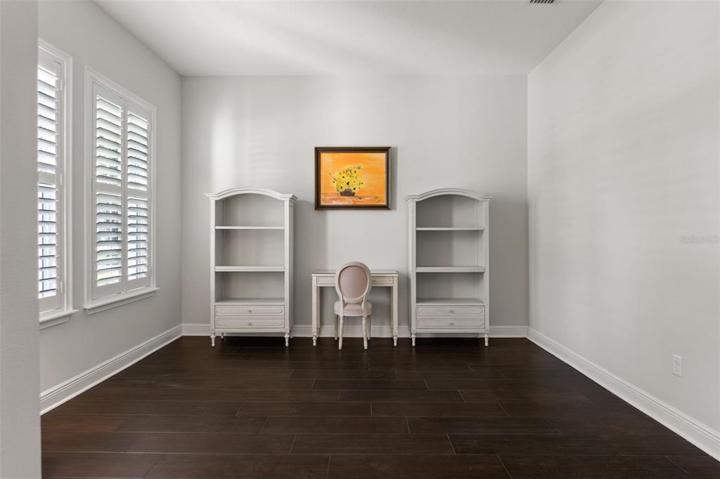 A home office features two white bookshelves, a small desk, and dark wood flooring — 2112 CARROLL LANDING DRIVE, TAMPA, FL