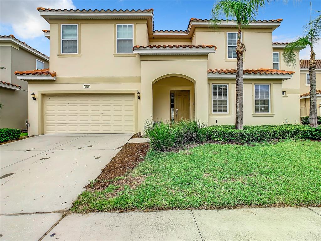 A two-story suburban house with a beige stucco exterior, tile roof, and a two-car garage — 6121 BROAD OAK DRIVE, DAVENPORT, FL