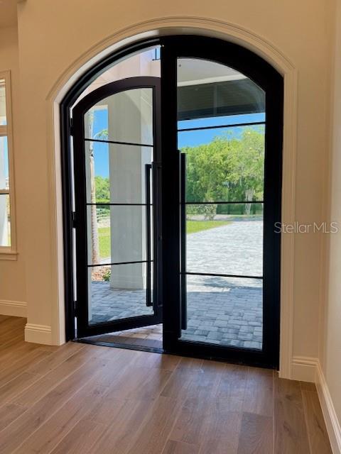 An arched black-framed glass door opens onto a stone patio with a view of trees — 26112 ESTATES RIDGE DRIVE, SORRENTO, FL