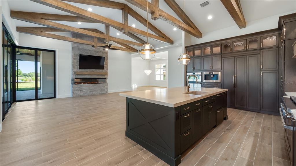 A kitchen with a dark island, wood-look tile floors, and exposed ceiling beams — 26112 ESTATES RIDGE DRIVE, SORRENTO, FL