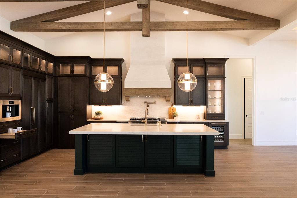 A kitchen features dark cabinetry, a large white island, and exposed wooden ceiling beams — 26112 ESTATES RIDGE DRIVE, SORRENTO, FL