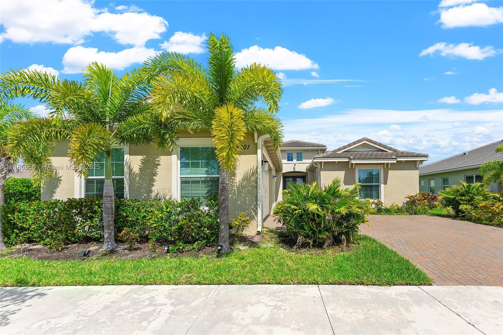 A tan single-story house features a brick driveway, palm trees, and a landscaped front yard — 15901 Meadowlark Ct, Loxahatchee FL 33470, LOXAHATCHEE, FL