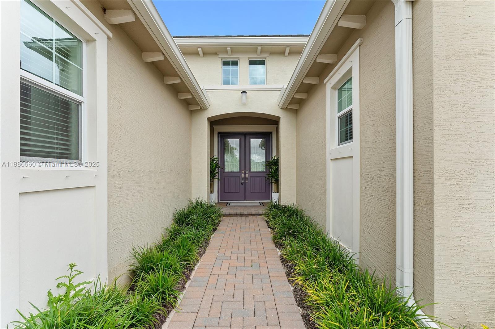 A brick walkway leads to a purple double-door entrance flanked by green plants — 15901 Meadowlark Ct, Loxahatchee FL 33470, LOXAHATCHEE, FL