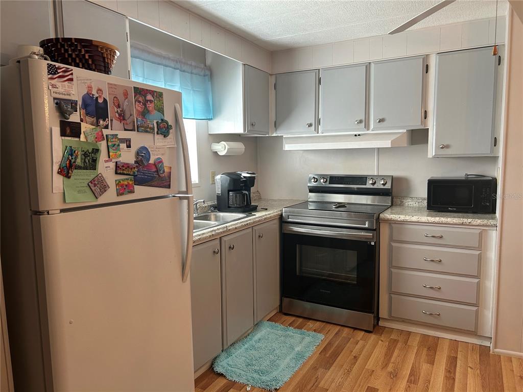 A kitchen features grey cabinets, stainless steel appliances, and light-colored countertops — 131 MALAYON WAY, LEESBURG, FL