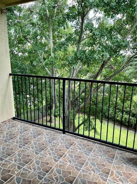 A balcony with stone-patterned tile flooring and a black metal railing overlooking trees — 2674 ROBERT TRENT JONES DRIVE UNIT 337, ORLANDO, FL