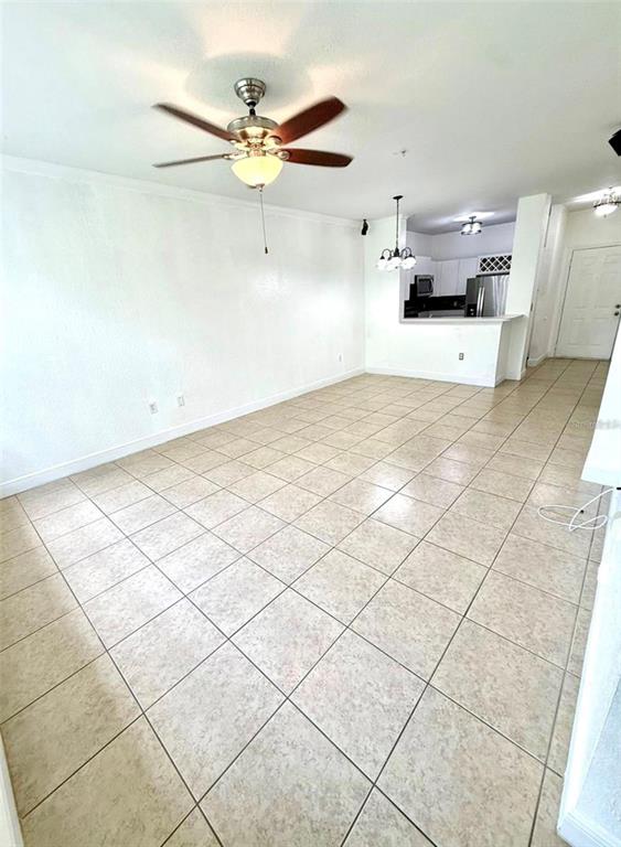 An open-concept living area features light-colored tile flooring, a ceiling fan, and a kitchen pass-through — 2674 ROBERT TRENT JONES DRIVE UNIT 337, ORLANDO, FL