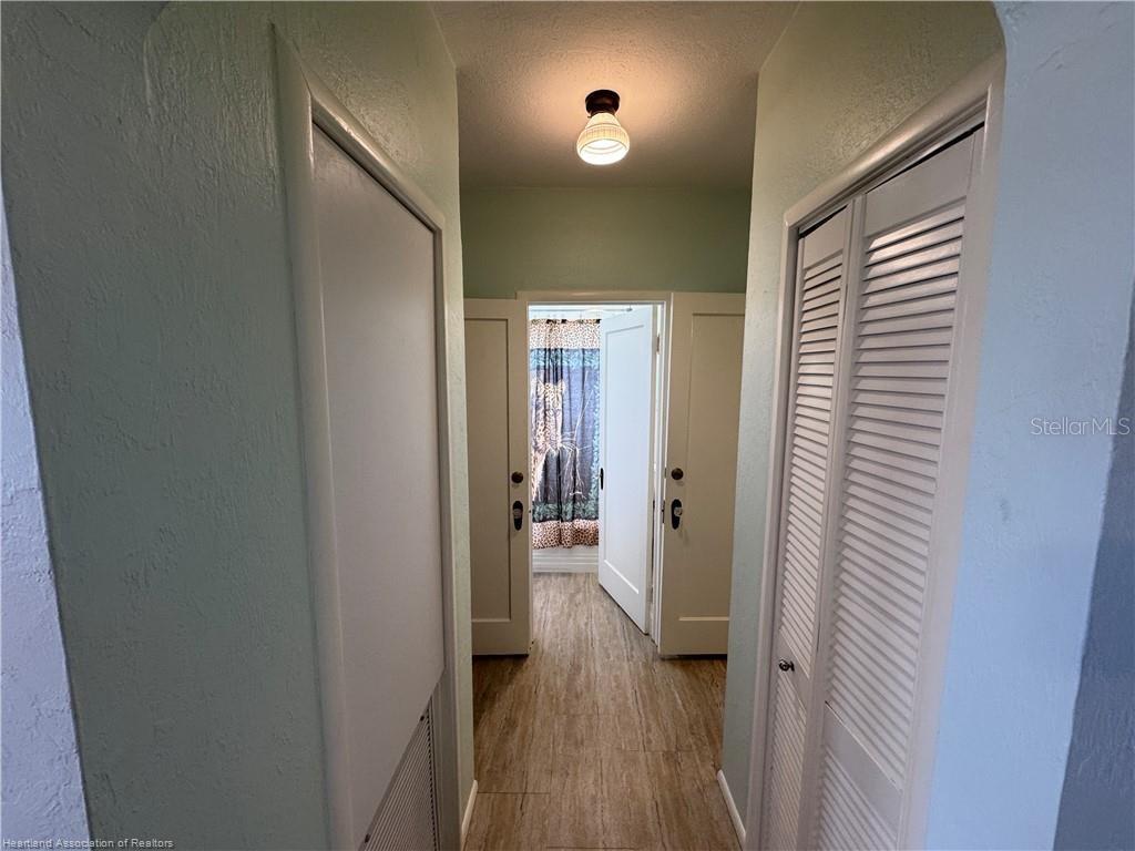 A hallway with louvered closet doors leads to a bathroom with a patterned shower curtain — 930 W MAIN STREET, AVON PARK, FL