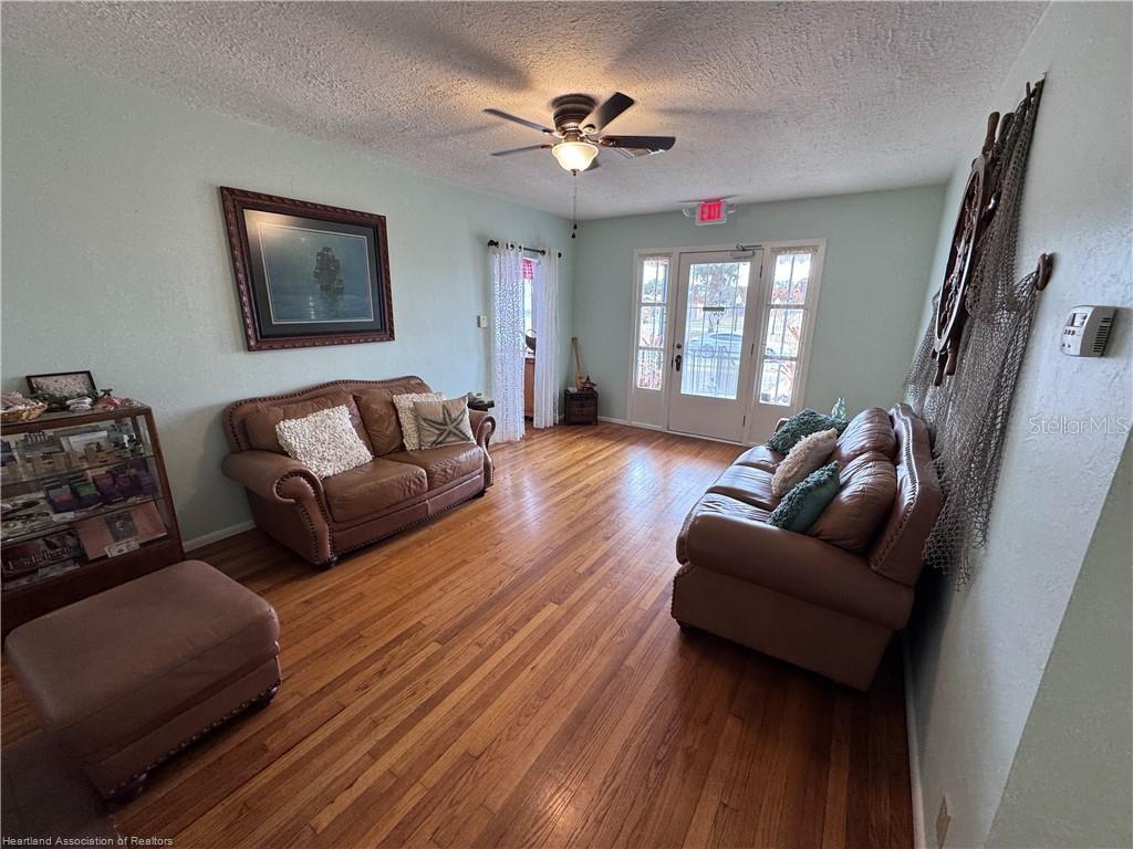 A living room features two leather sofas, hardwood floors, and a nautical-themed wall decoration — 930 W MAIN STREET, AVON PARK, FL