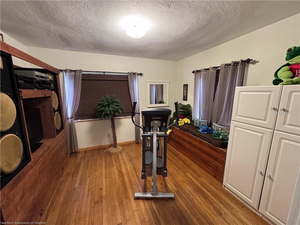 A room with hardwood floors, an elliptical machine, a window seat, and wooden cabinetry — 930 W MAIN STREET, AVON PARK, FL