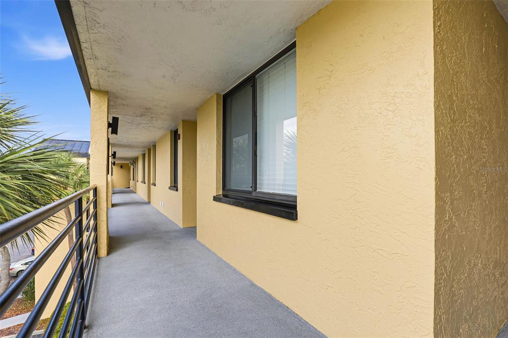 An outdoor balcony with yellow stucco walls, a metal railing, and a concrete floor — 2424 W TAMPA BAY BOULEVARD UNIT M404, TAMPA, FL