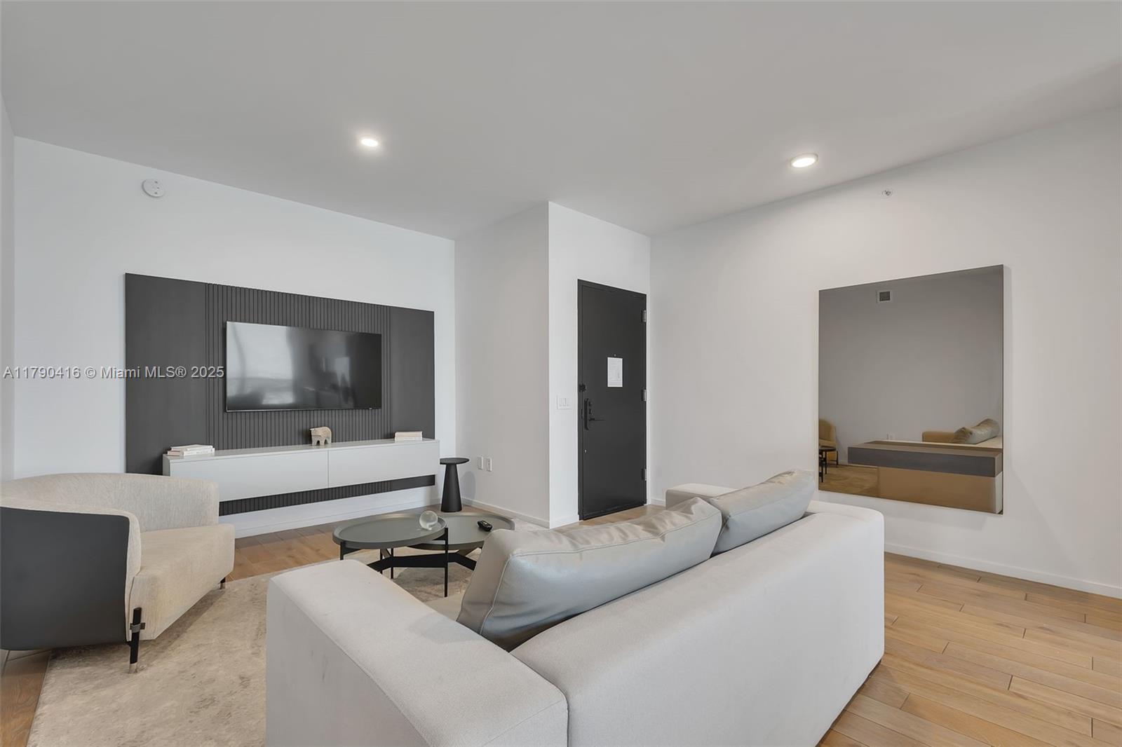 This living room features a wall-mounted television, a grey sofa, and light wood flooring — 398 NE 5th St # 3901, Miami FL 33132, MIAMI, FL