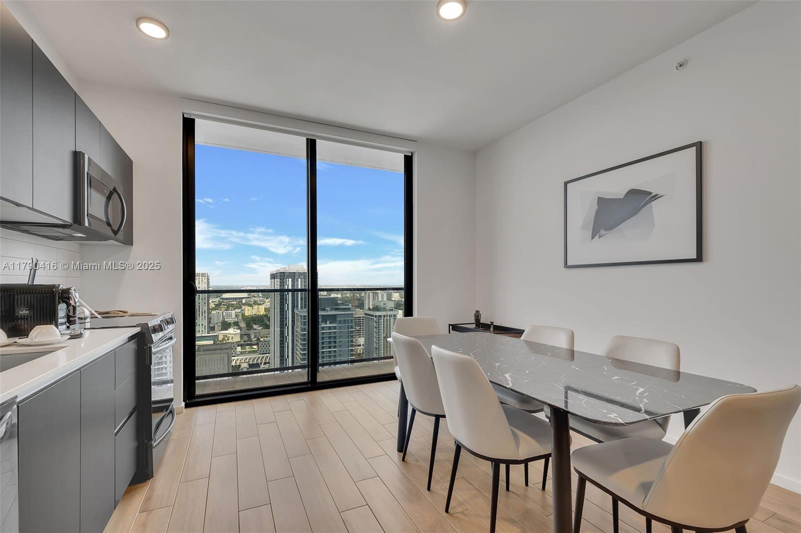 A kitchen and dining area features dark cabinetry, a marble table, and floor-to-ceiling windows — 398 NE 5th St # 3901, Miami FL 33132, MIAMI, FL