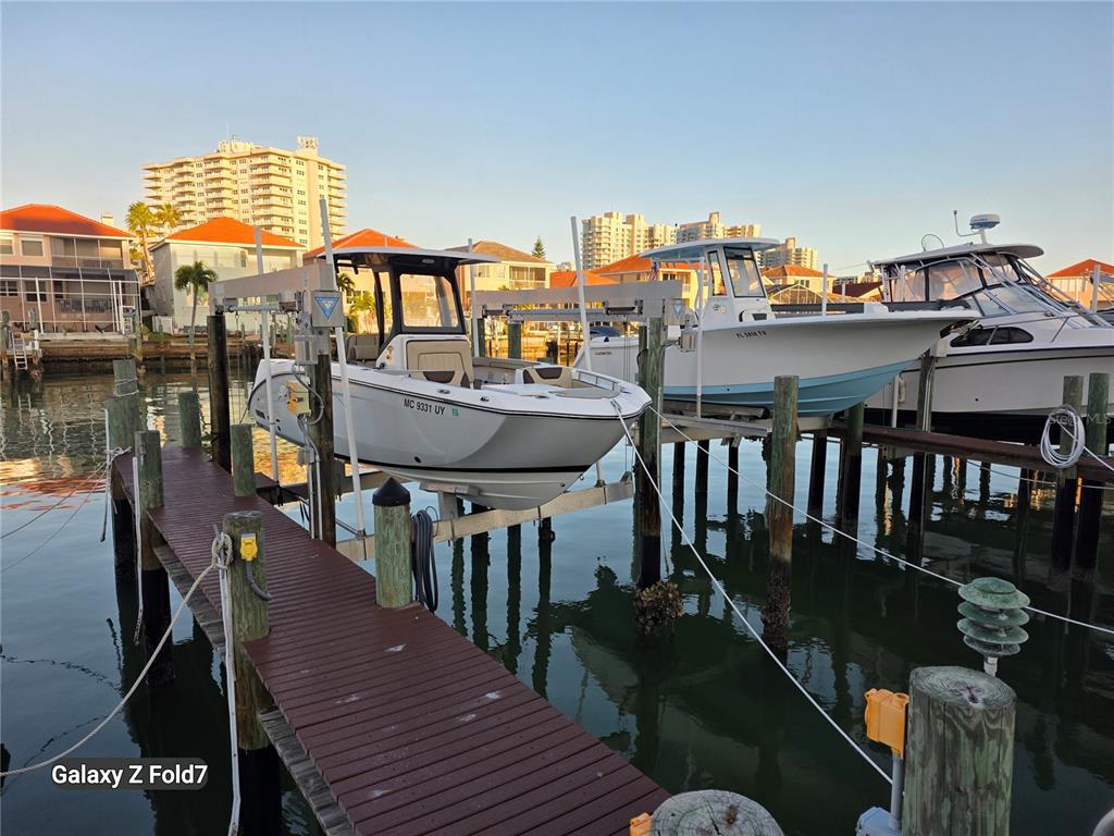 Three boats are docked on lifts at a wooden pier in front of waterfront homes — 240 SAND KEY ESTATES DRIVE UNIT 222, CLEARWATER, FL