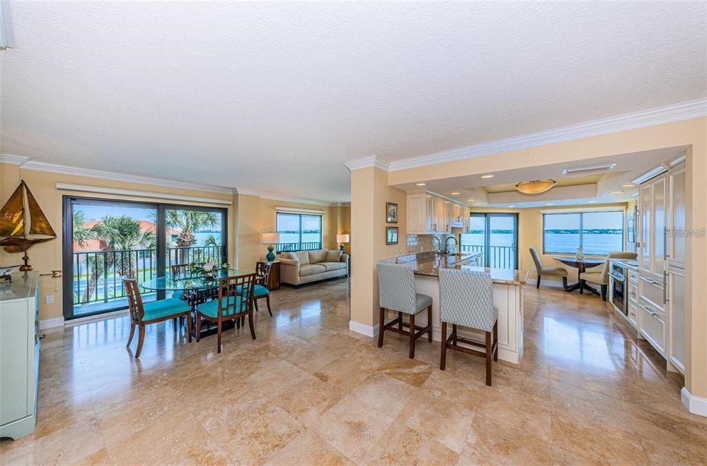 An open-concept kitchen and dining area with tile floors, a breakfast bar, and water views — 240 SAND KEY ESTATES DRIVE UNIT 222, CLEARWATER, FL