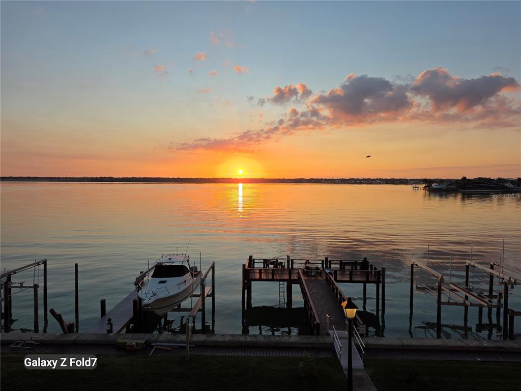 A sunset view over a calm body of water with a boat dock and boat — 240 SAND KEY ESTATES DRIVE UNIT 222, CLEARWATER, FL