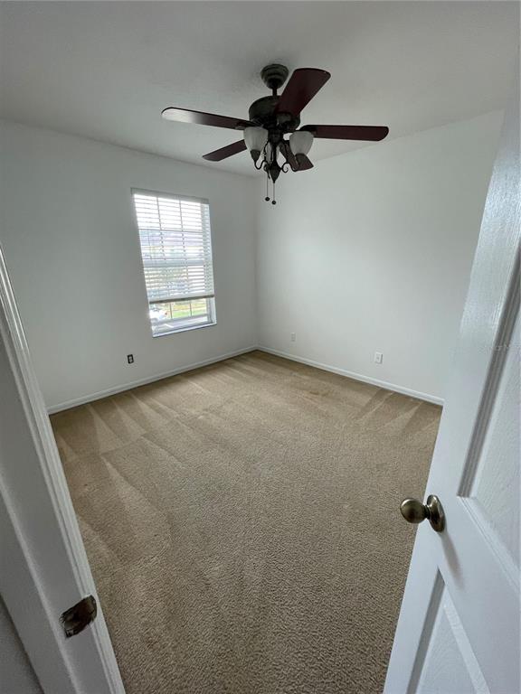 An empty bedroom features beige carpet, white walls, a window with blinds, and a ceiling fan — 765 CRESTING OAK CIRCLE UNIT 127, ORLANDO, FL