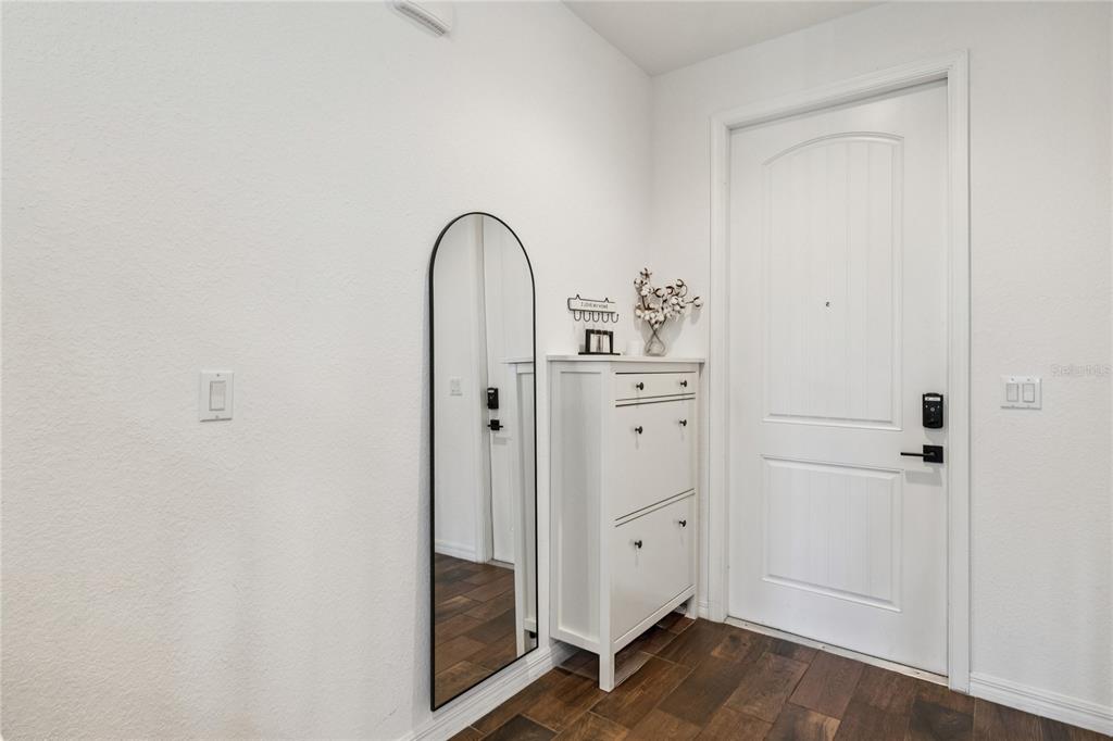 An entryway features a white shoe cabinet, an arched floor mirror, and a white door — 1169 SEPIA LANE, LAKE WORTH, FL