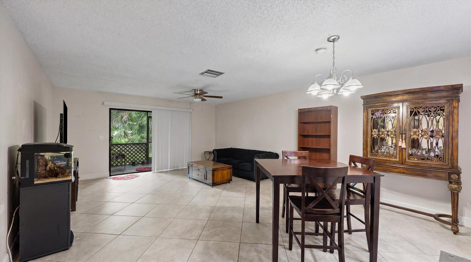A living and dining area with tile floors, a ceiling fan, and a sliding glass door — 1303 Lakeview E, Royal Palm Beach FL 33411, ROYAL PALM BEACH, FL