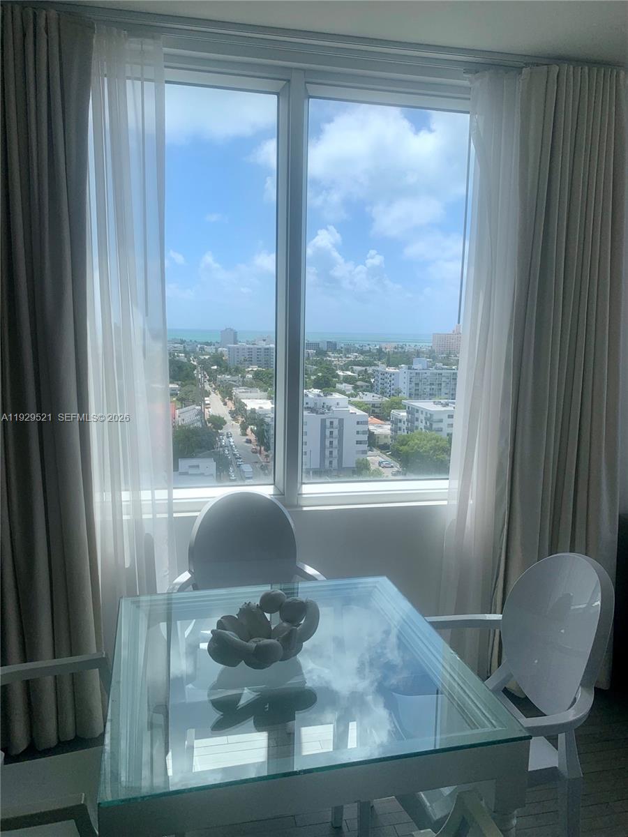 A glass-topped dining table with modern chairs sits before a large window overlooking a city — 1100 West Ave # 1601, Miami Beach FL 33139, MIAMI BEACH, FL