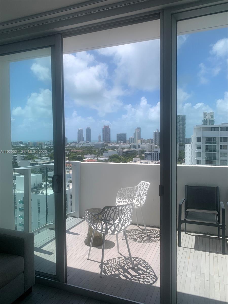 A balcony with two white patterned chairs overlooks a city skyline under a blue sky — 1100 West Ave # 1601, Miami Beach FL 33139, MIAMI BEACH, FL
