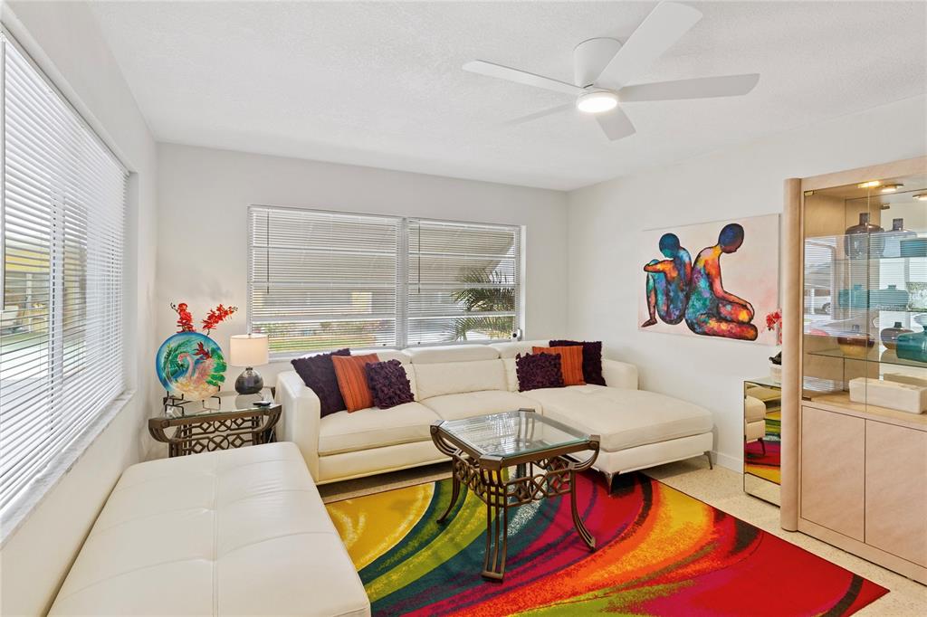 A living room features a white sectional sofa, a colorful area rug, and a ceiling fan — 250 ROSERY ROAD NW UNIT 280, LARGO, FL