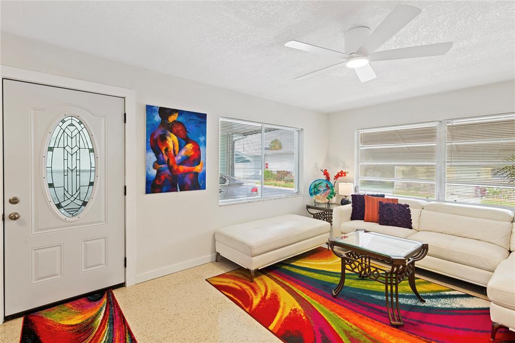 A living room features a white sofa, a colorful area rug, and a front door — 250 ROSERY ROAD NW UNIT 280, LARGO, FL