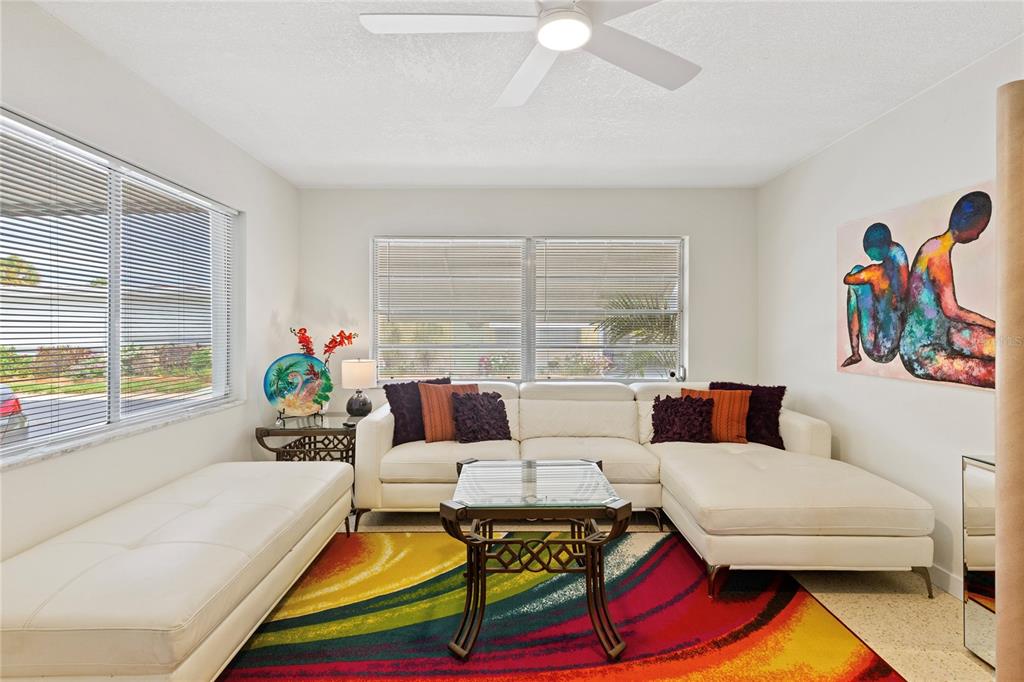 A living room features a white sectional sofa, a colorful area rug, and two windows — 250 ROSERY ROAD NW UNIT 280, LARGO, FL