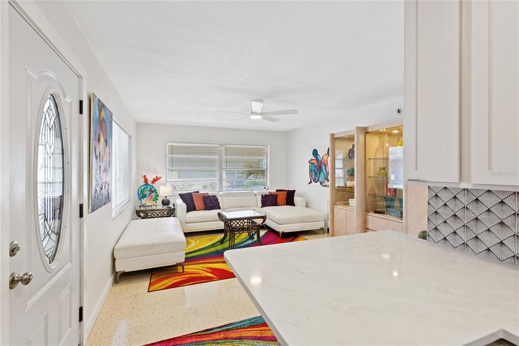 A bright living room features a white sectional sofa, colorful area rug, and glass display cabinets — 250 ROSERY ROAD NW UNIT 280, LARGO, FL