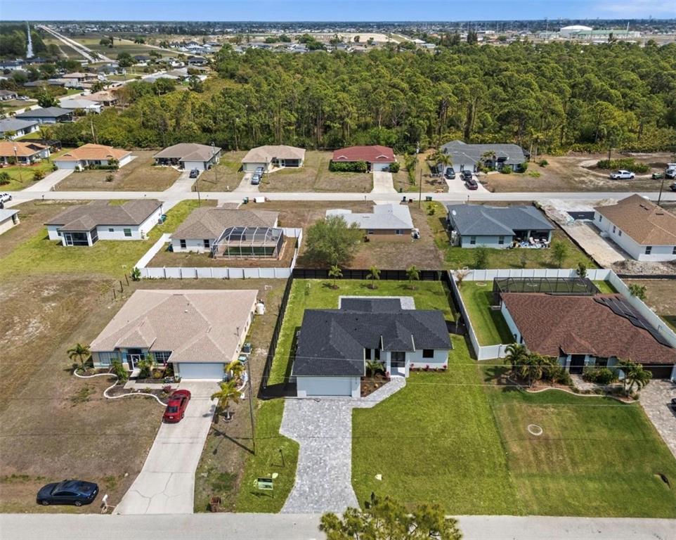 An aerial view shows a suburban neighborhood with single-family homes and paved driveways — 409 NW 25TH PLACE, CAPE CORAL, FL
