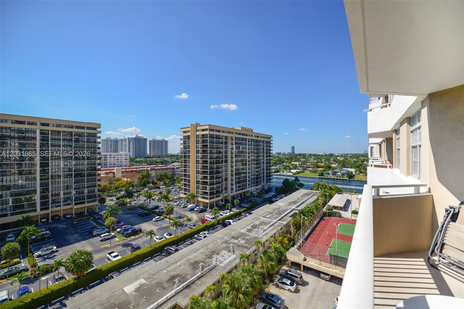 An elevated view from a balcony overlooks a parking lot, apartment buildings, and a canal — 1985 S Ocean Dr # 4G, Hallandale Beach FL 33009, HALLANDALE BEACH, FL