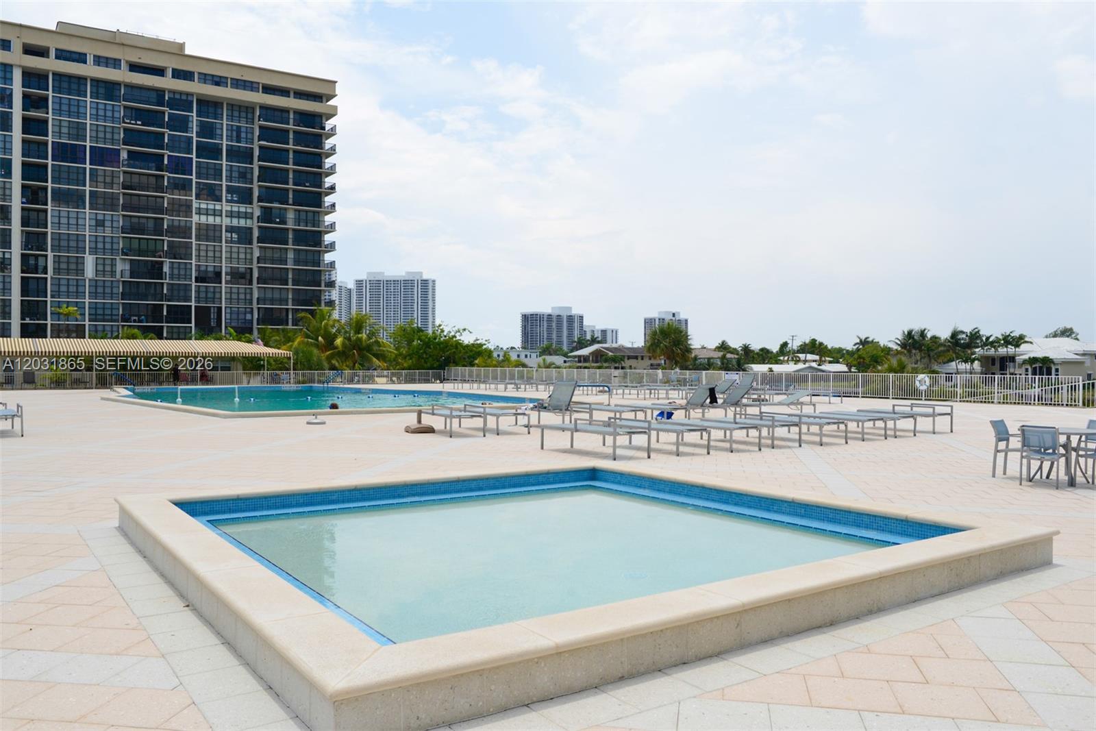 A pool deck features a small square spa, a larger swimming pool, and lounge chairs — 1985 S Ocean Dr # 4G, Hallandale Beach FL 33009, HALLANDALE BEACH, FL